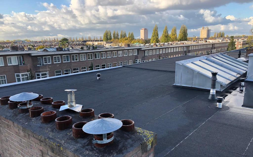 Vernieuwd plat dak met schoorsteenpotten en dakkapellen boven Amsterdam