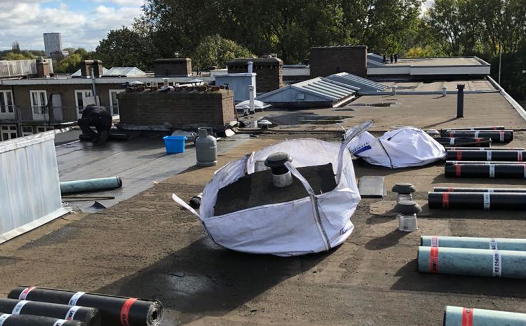 Dakbedekking in uitvoering, rollen en materiaal op een plat dak